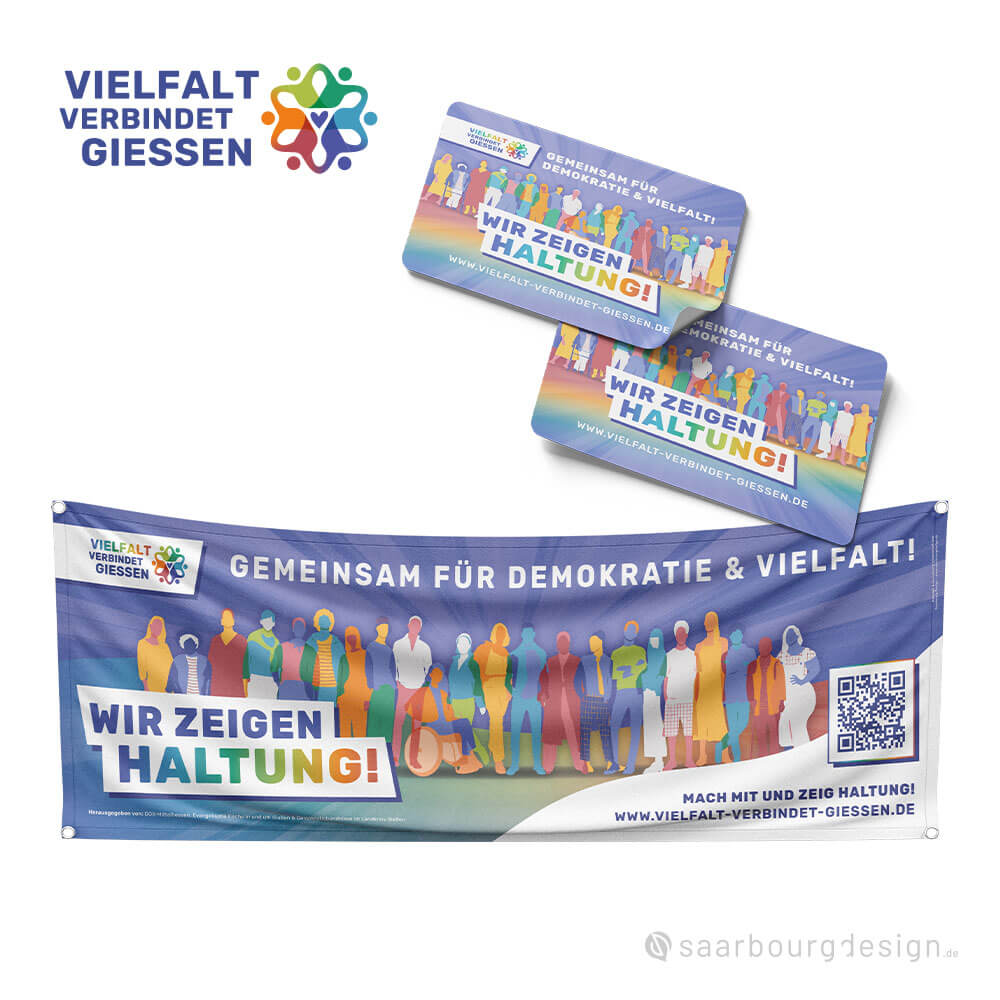 Zwei Aufkleber und ein Banner der Demokratie-Kampagne „Vielfalt verbindet Gießen“ mit dem Schriftzug „Wir zeigen Haltung!“ in buntem Design.